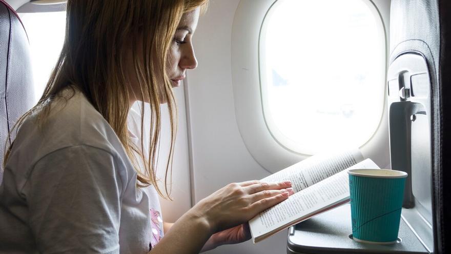 Mujer leyendo un libro en un avión.