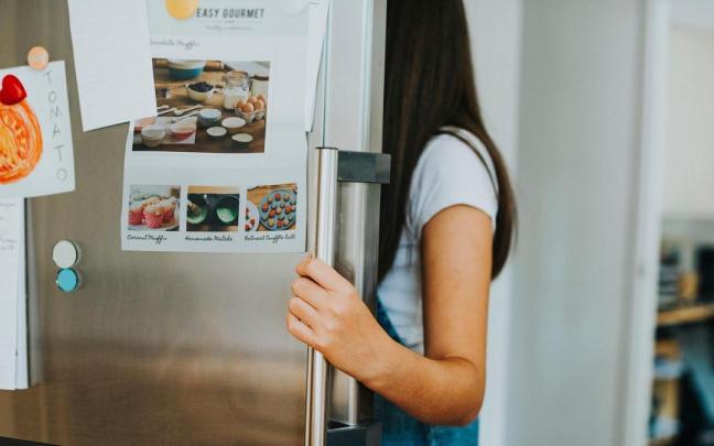 Puerta de un frigorífico llena de imanes y papeles.