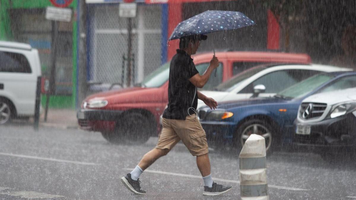Un hombre se cubre de la lluvia intensa con un paraguas.