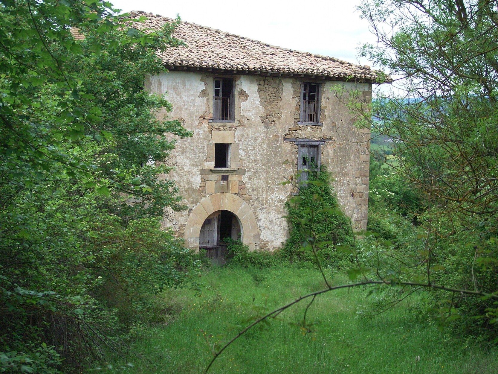 Una vieja casa abandonada, rodeada de vegetación en el despoblado de Larrangoz.