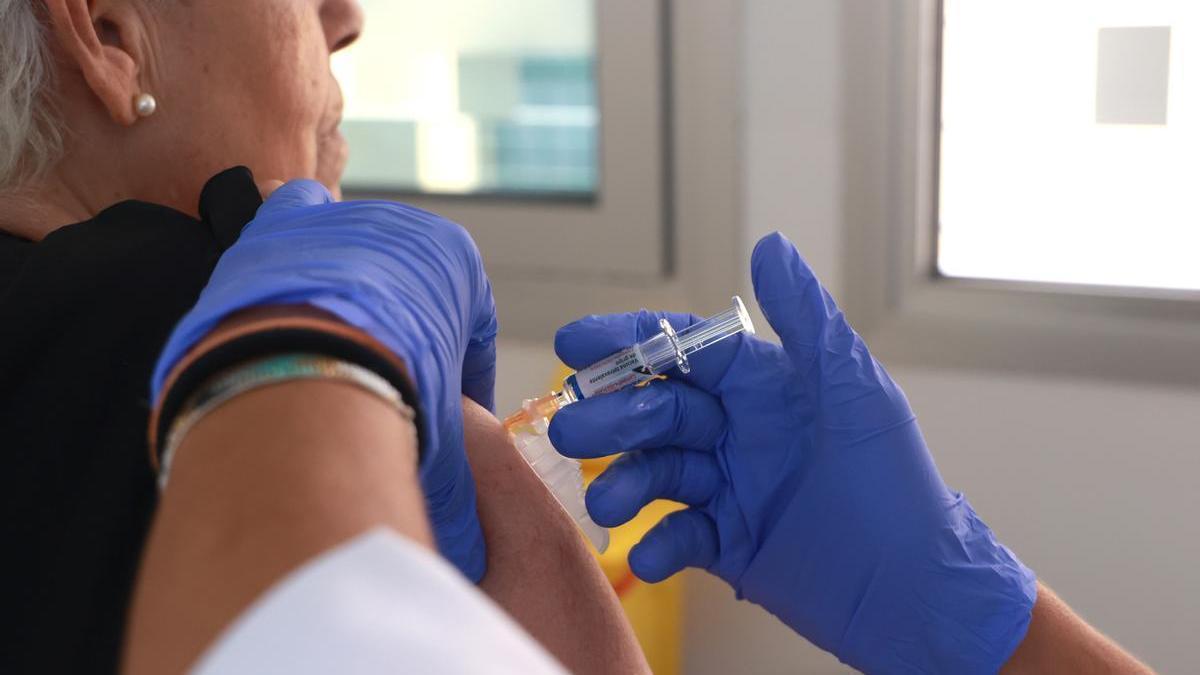 Una sanitaria inocula la vacuna de la gripe a una mujer.