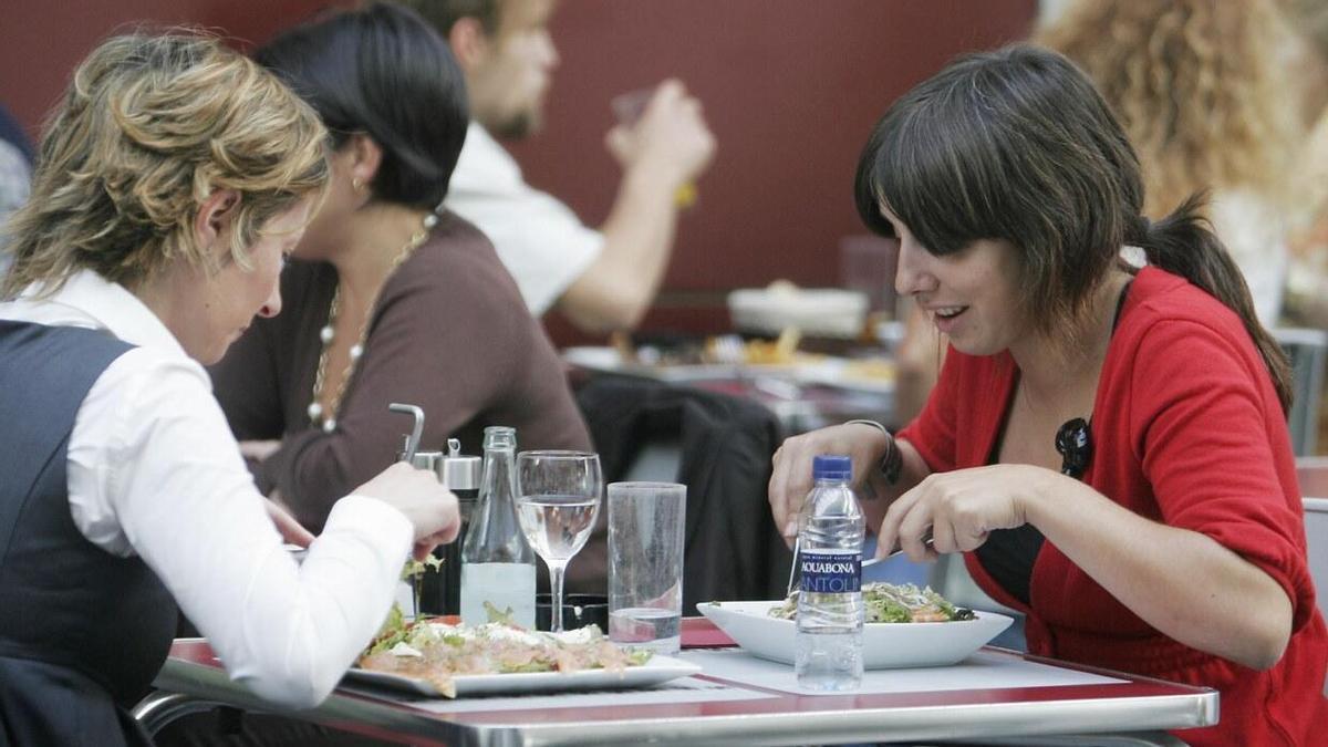 Dos mujeres comen con agua en la terraza de un restaurante.