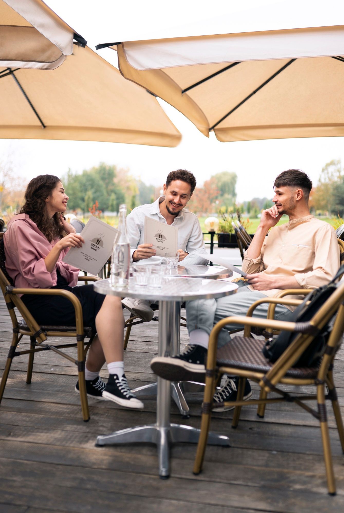Tres amigos consultan el menú en la terraza de un bar.