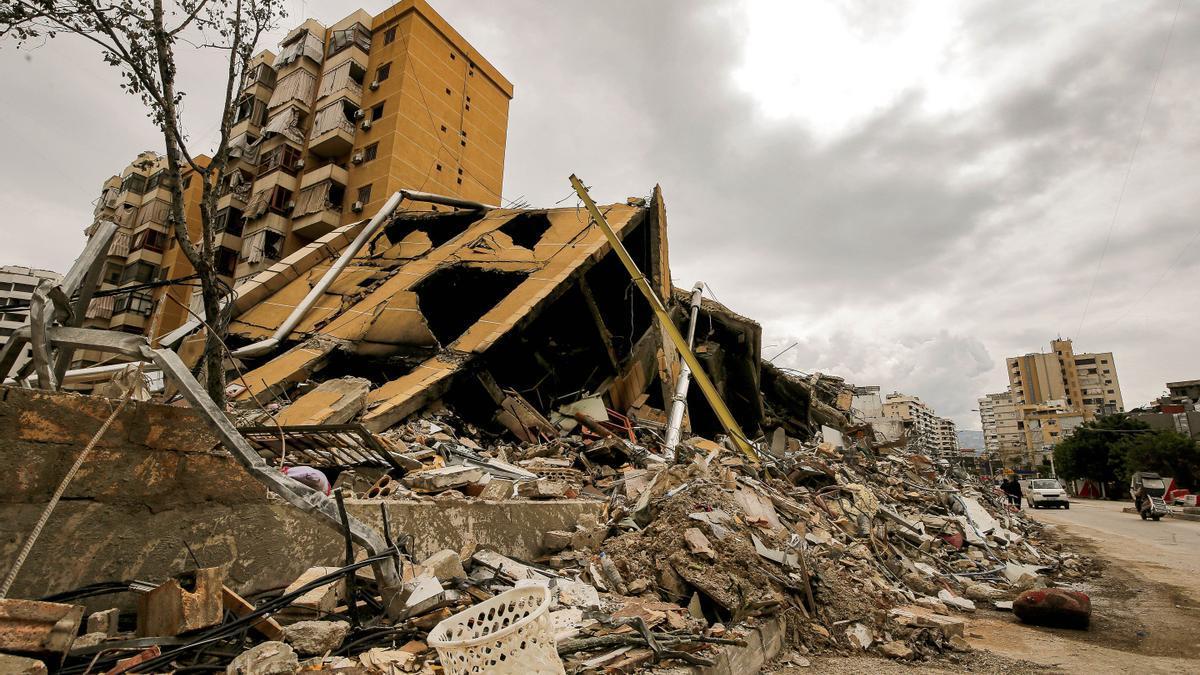 La gente pasa junto a un edificio destruido en las afueras del devastado barrio del sur de Beirut