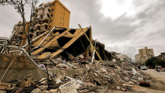 La gente pasa junto a un edificio destruido en las afueras del devastado barrio del sur de Beirut
