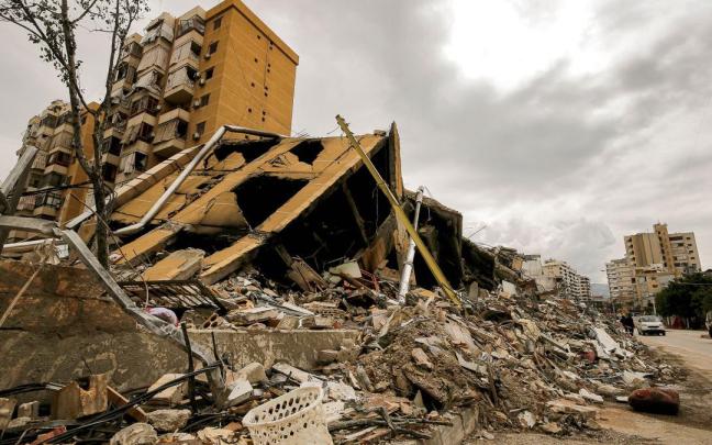 La gente pasa junto a un edificio destruido en las afueras del devastado barrio del sur de Beirut