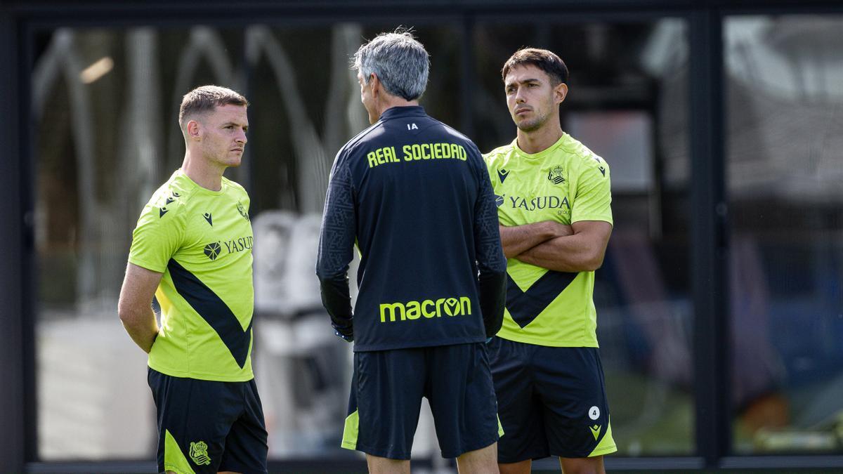 Sergio Gómez y Zubimendi charlan con Imanol, durante el entrenamiento vespertino de este lunes en Zubieta. / REAL SOCIEDAD