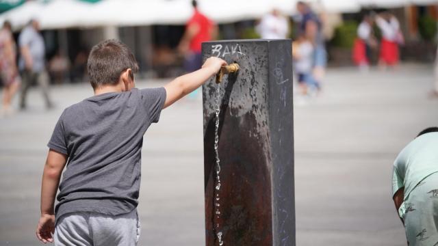 Un niño llena usa una fuente para refrescarse.