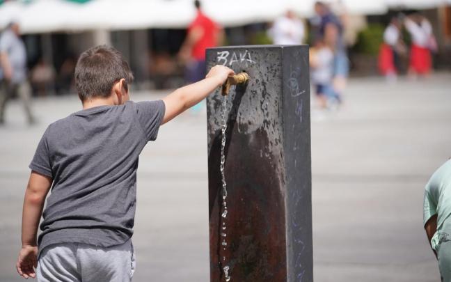 Un niño llena usa una fuente para refrescarse.