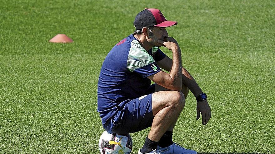 Ernesto Valverde, sentado sobre un balón, mientras observa un entrenamiento de sus futbolistas en Lezama. | FOTO: OSKAR M. BERNAL