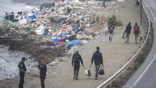 Agentes de la Policía Nacional intervienen durante el proceso de desalojo del embolsamiento de migrantes en la playa de El Trampolín