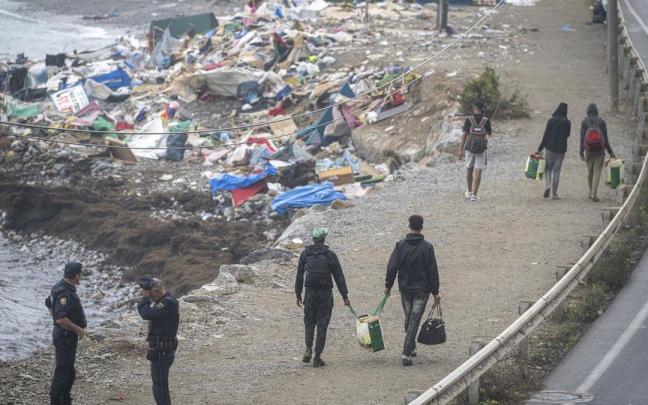 Agentes de la Policía Nacional intervienen durante el proceso de desalojo del embolsamiento de migrantes en la playa de El Trampolín