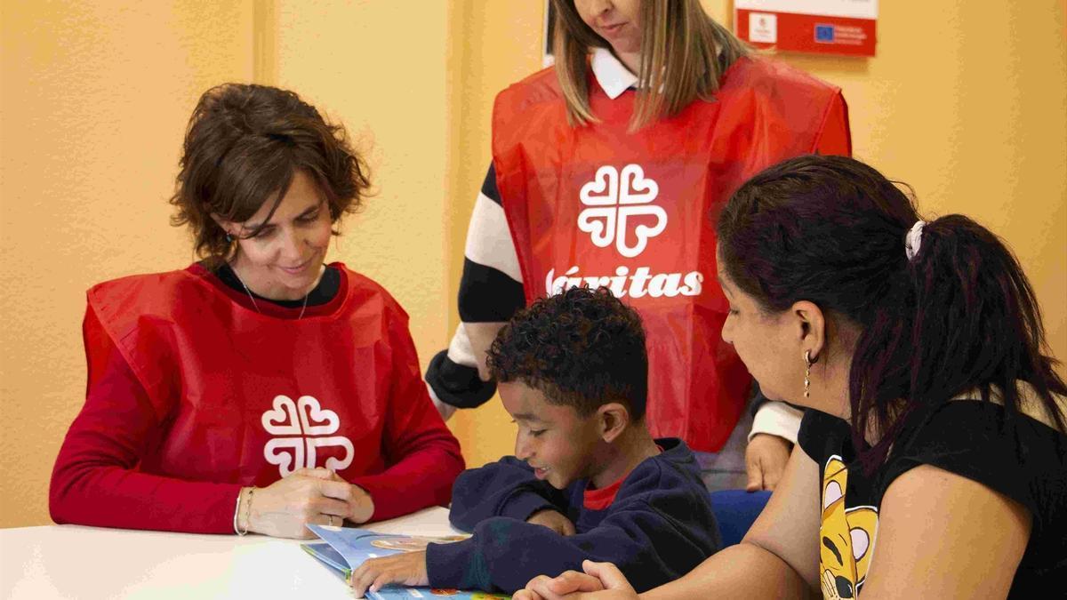 Un niño y su madre junto a dos técnicos de Cáritas.