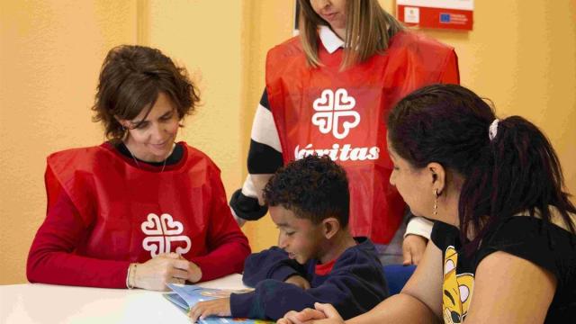 Un niño y su madre junto a dos técnicos de Cáritas.