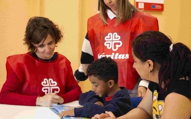 Un niño y su madre junto a dos técnicos de Cáritas.