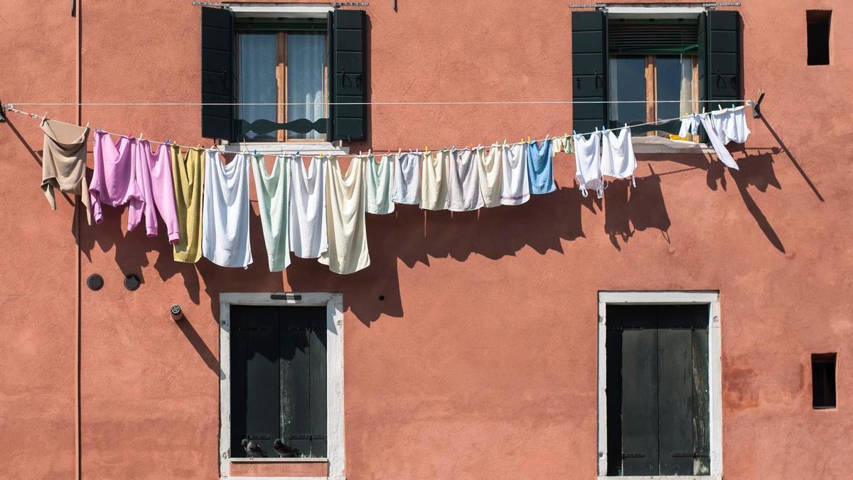 Ropa tendida en cuerdas en la fachada de un edificio.