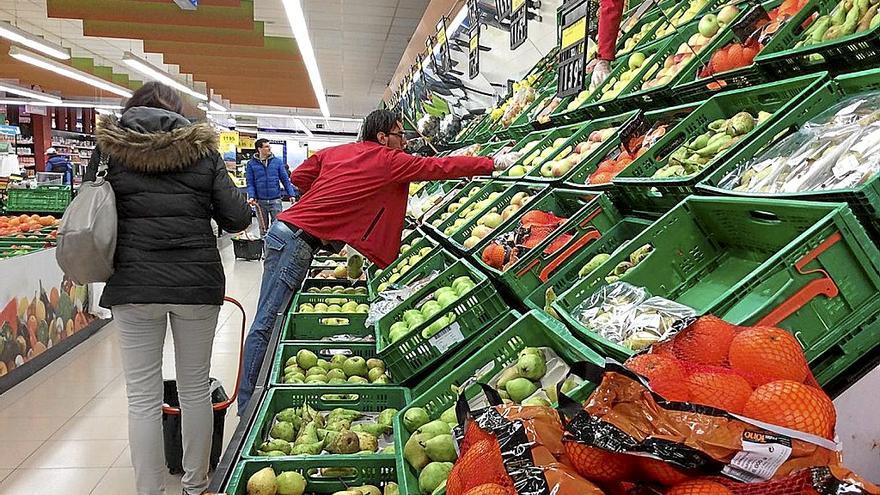 Varias personas hacen la compra en un supermercado.