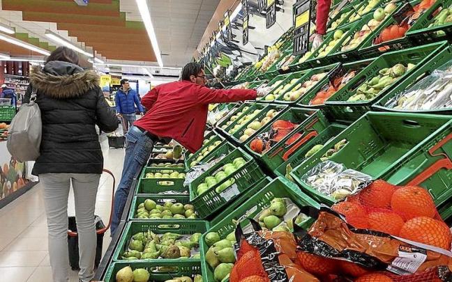 Varias personas hacen la compra en un supermercado.