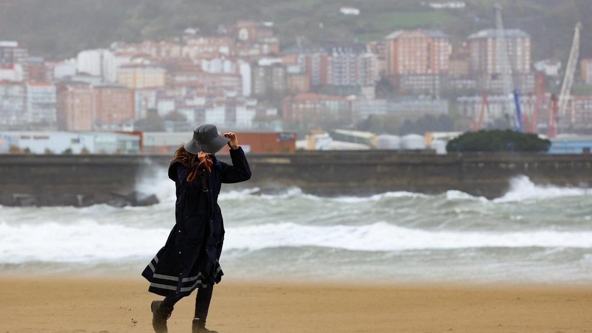 Una mujer pasea por Ereaga durante un temporal de viento y lluvia.