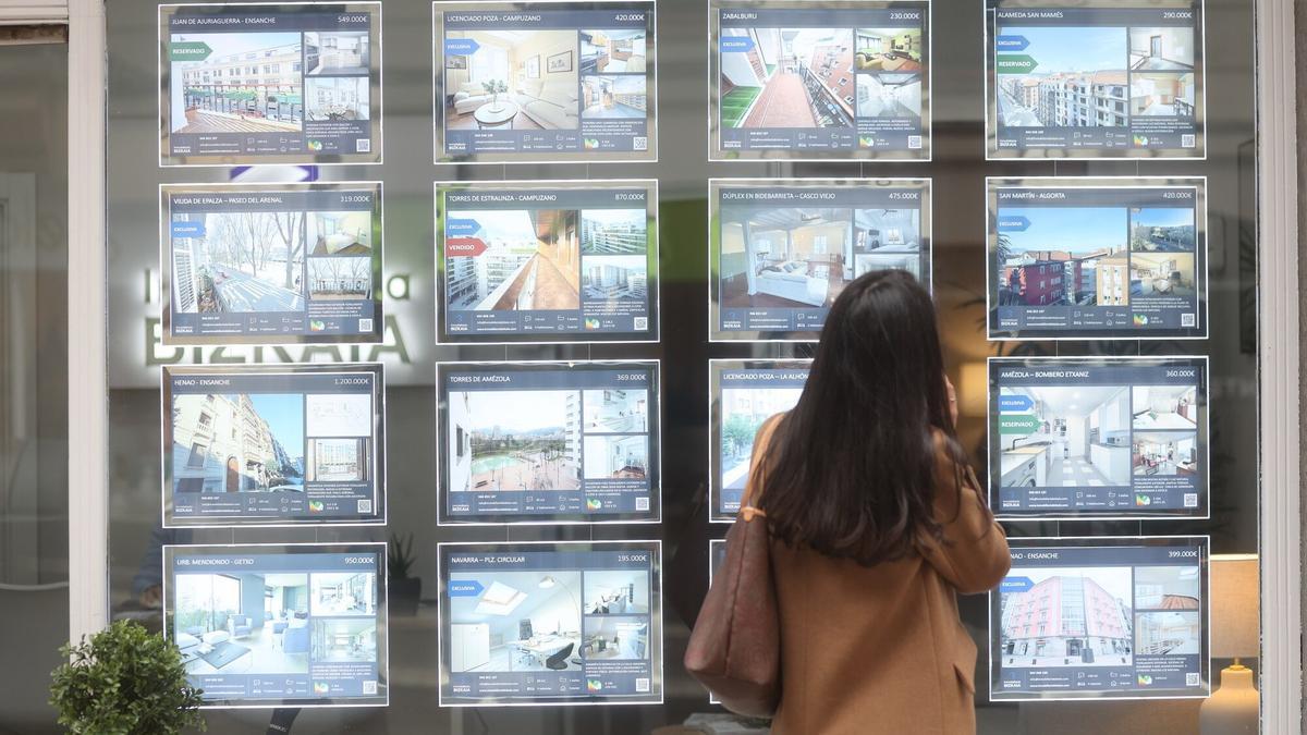 Una mujer observa las ofertas de pisos de una inmobiliaria