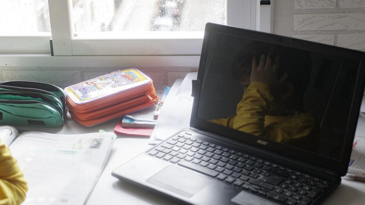 Un escolar estudiando junto a su ordenador portátil.