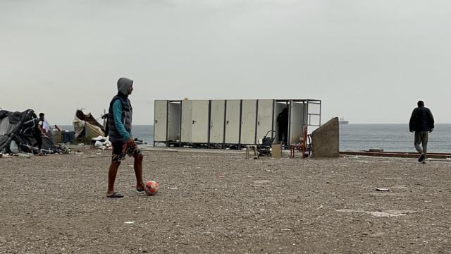 Varios migrantes esperan a ser trasladados en la explanada del Guano.