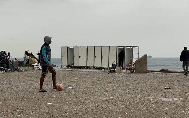Varios migrantes esperan a ser trasladados en la explanada del Guano.