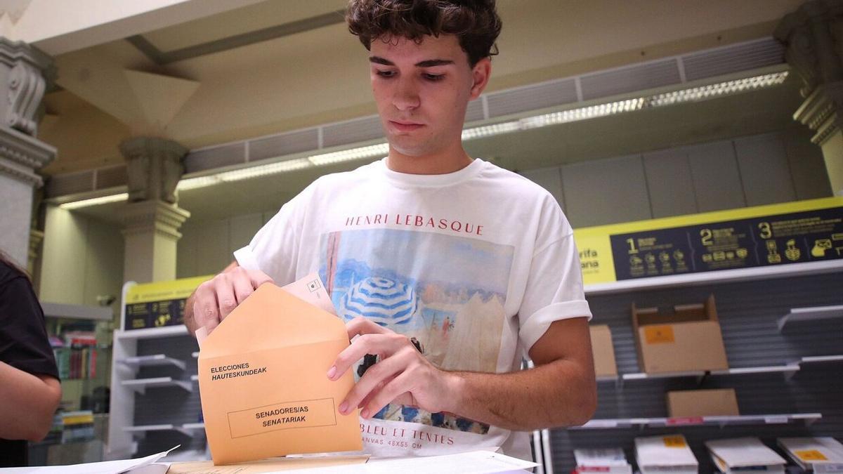 Un joven introduce la papeleta de su elección al Senado, en la oficina de Correos del Paseo Sarasate de Pamplona.
