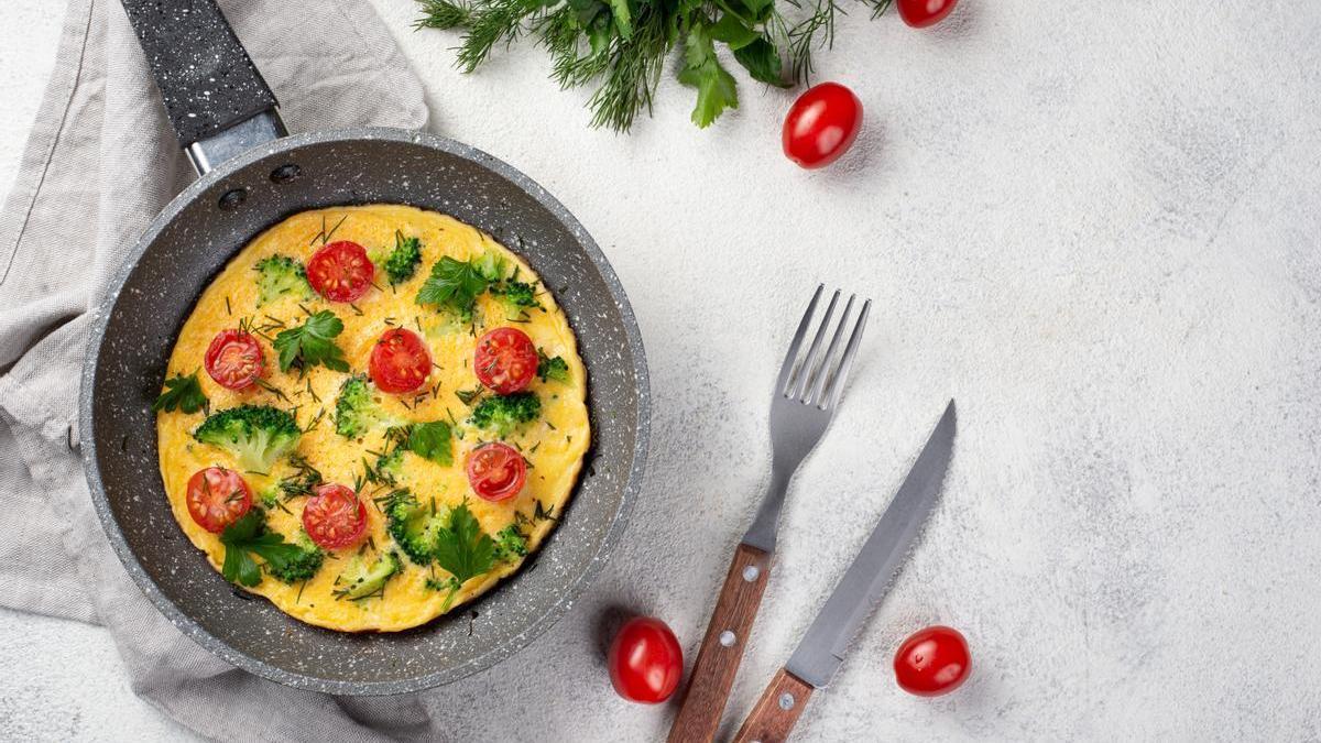Tortilla francesa con tomates cherry y verduras en la sartén.