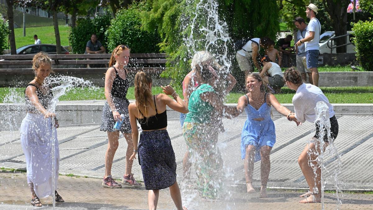 Un grupo de chicas se refresca del tórrido calor en los chorros de agua existentes en los aledaños del Museo Guggenheim.
