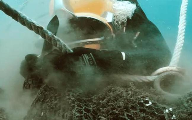 Un voluntario trabajando para sacar una red del fondo marino.