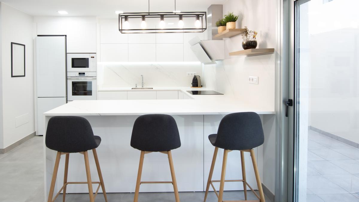 Taburetes negros con patas de madera en una cocina moderna con barra.