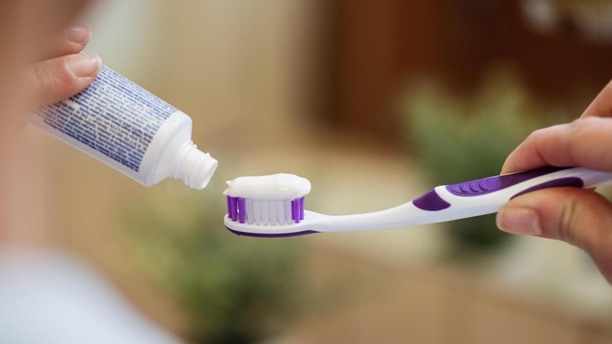 Una mujer pone dentífrico en un cepillo de dientes.