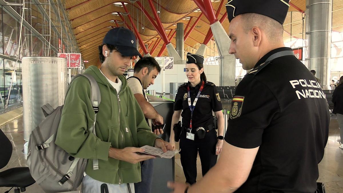 Un par de agentes de la Policía Nacional revisan la documentación de unos viajeros en el aeropuerto de Barcelona.