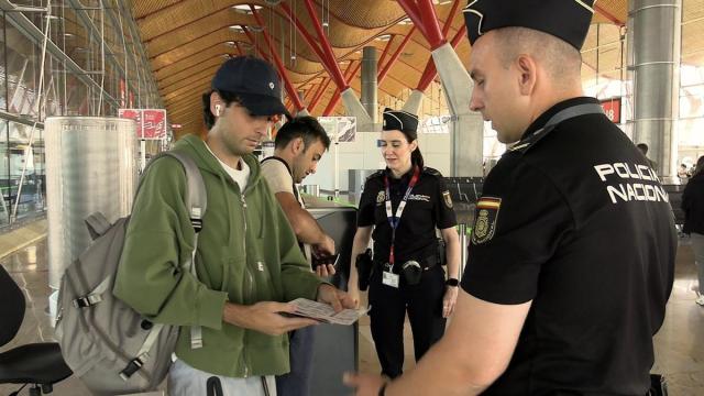 Un par de agentes de la Policía Nacional revisan la documentación de unos viajeros en el aeropuerto de Barcelona.