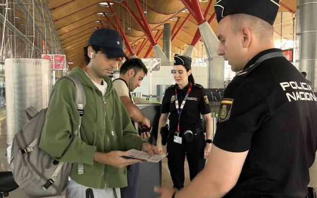 Un par de agentes de la Policía Nacional revisan la documentación de unos viajeros en el aeropuerto de Barcelona.