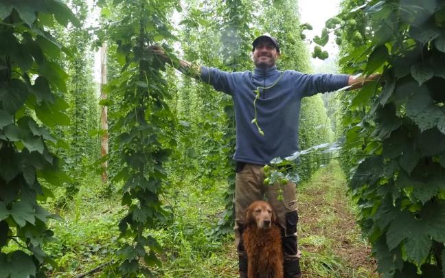 Asier Plazaola y su inseparable compañero 'Pepe', flanqueados por las plantas de lúpulo que crecen en su explotación de Azkoitia.