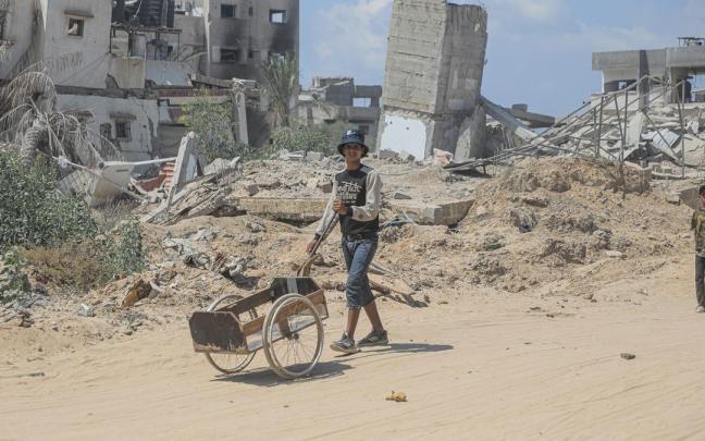 Palestinos entre los escombros de edficios destruidos en Jan Yunis.