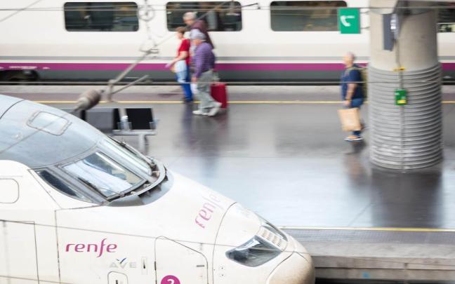 Viajeros con maletas en una estación de trenes.
