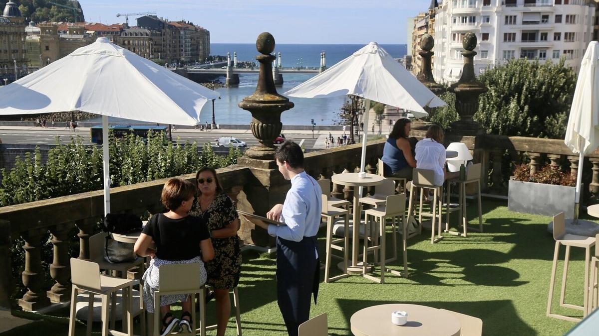 Un camarero atiende a unas clientas en un terraza de Donostia