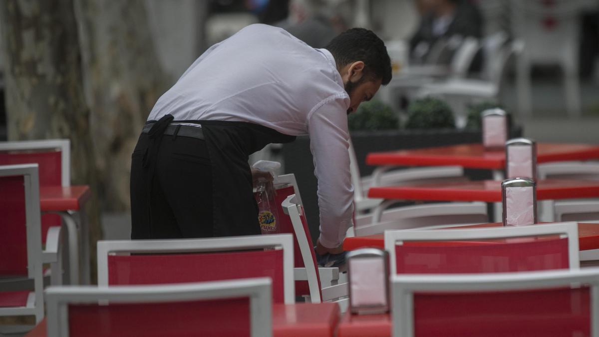 Un camarero acondiciona una terraza.