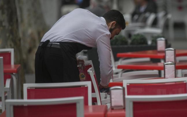 Un camarero acondiciona una terraza.