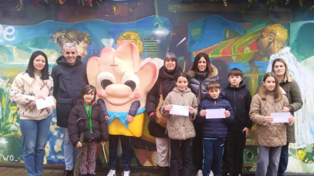 La mascota, Beldekartxo, acompaña la entrega de los premios del juego navideño por los escaparates.