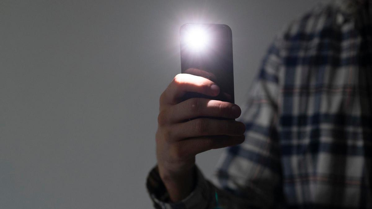 Una persona sostiene un teléfono móvil con la linterna encendida.