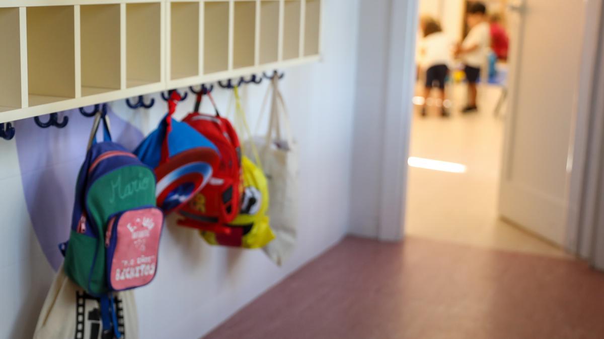 Varias mochilas en una percha de un aula de 0 a 3 años en un colegio