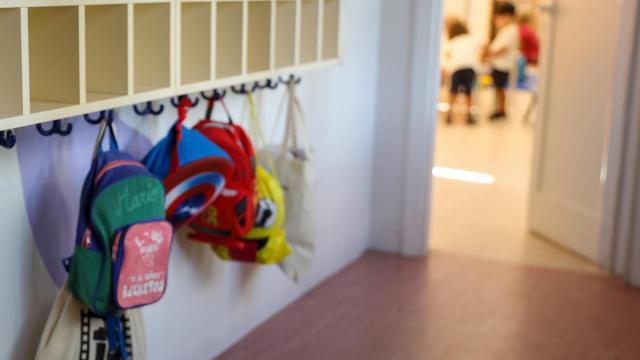 Varias mochilas en una percha de un aula de 0 a 3 años en un colegio
