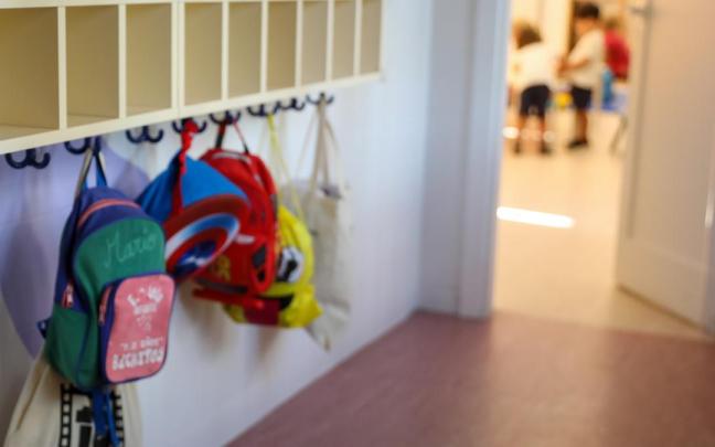 Varias mochilas en una percha de un aula de 0 a 3 años en un colegio