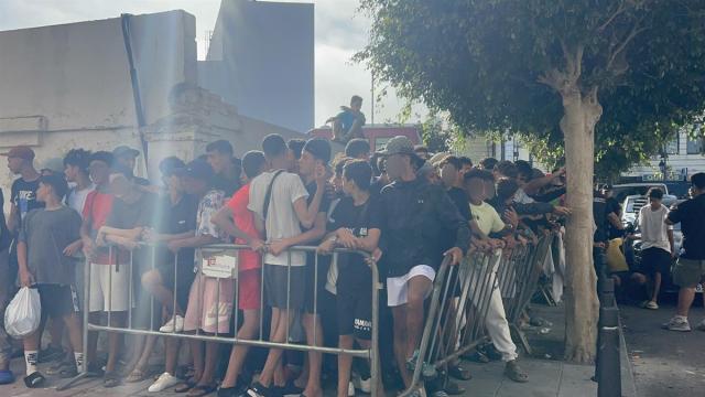 Un grupo de menores espera a las puertas de la Jefatura Superior de Policía de Ceuta para que les registren, 7 de agosto de 2026, en Ceuta.