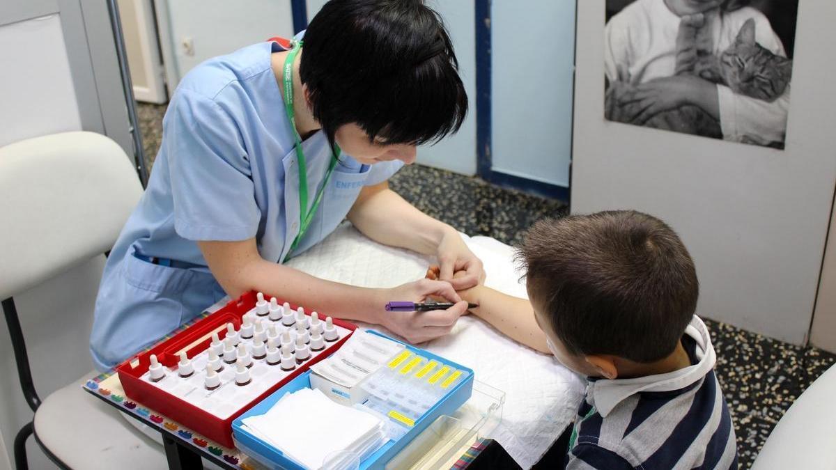 Una sanitaria realiza una prueba de alergia a un niño.