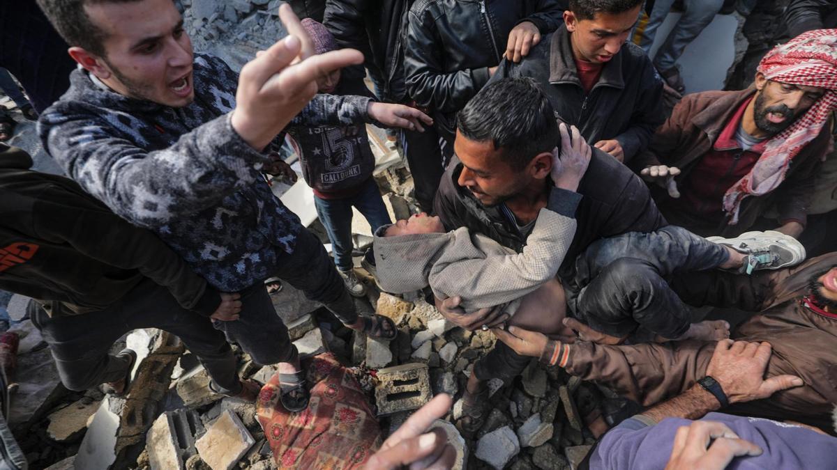 Palestinos recuperan a un niño herido entre los escombros de una casa destruida tras un ataque aéreo israelí en la localidad de Deir Al Balah, al sur de la Franja de Gaza.